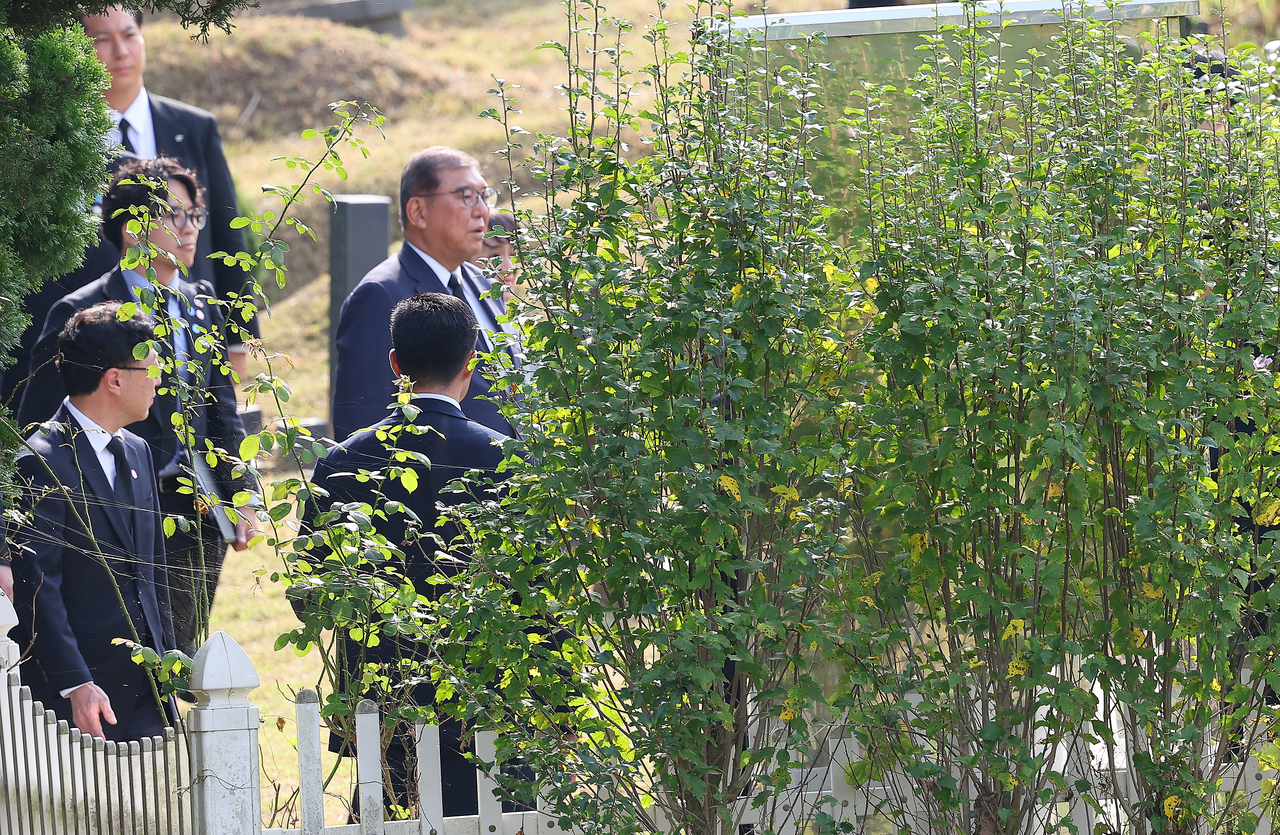 Japanese Prime Minister Shigeru Ishiba (second row, right) visits the grave of the late Lee Soo-hyun, a Korean student who was killed while rescuing a Japanese man at a train station in Tokyo in 2001, during his visit to Busan for a summit with President Lee Jae Myung on Tuesday. (Yonhap)