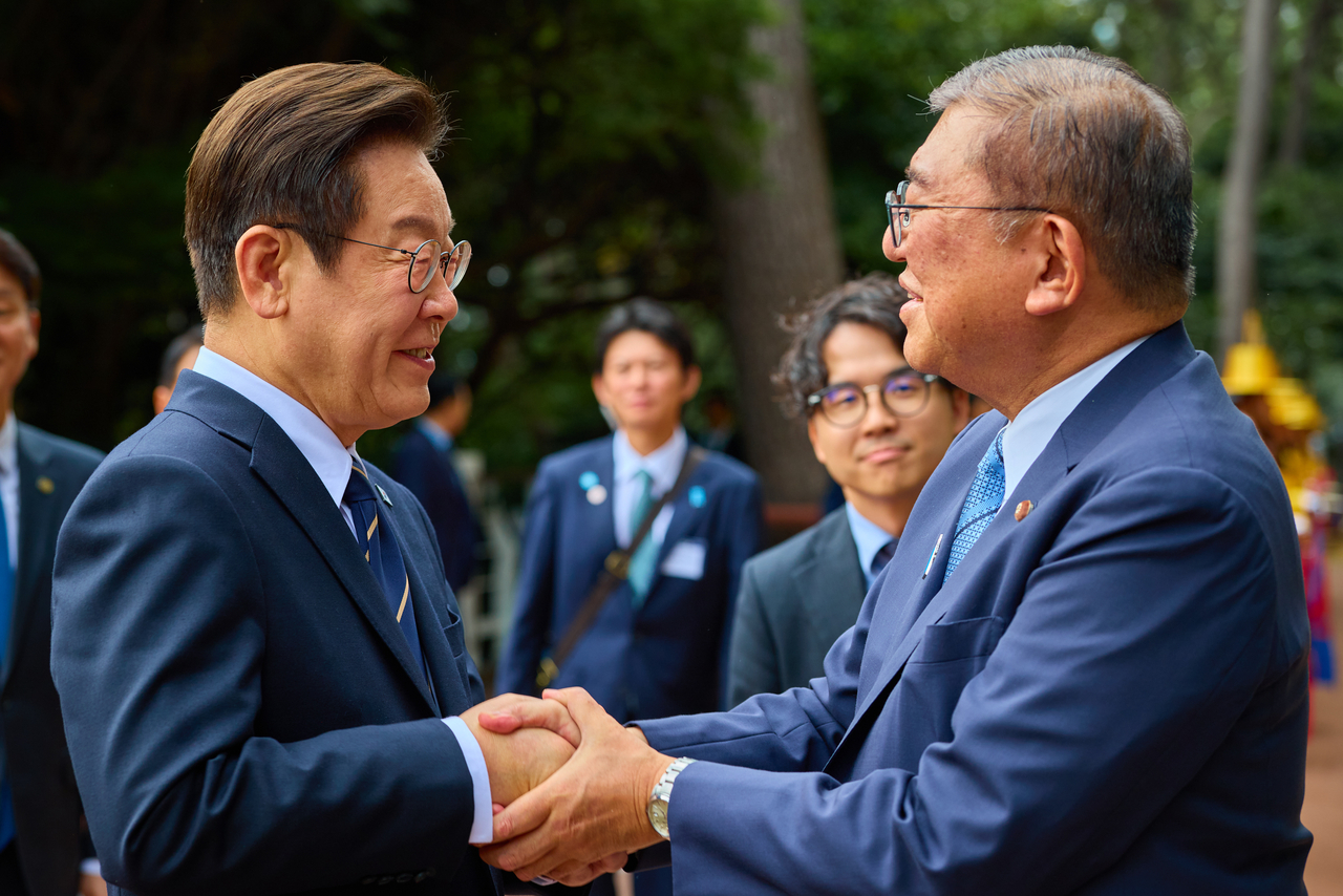 President Lee Jae Myung (left) and Japanese Prime Minister Shigeru Ishiba shake hands after concluding their summit at the Nurimaru APEC House in Busan on Tuesday. (Yonhap)