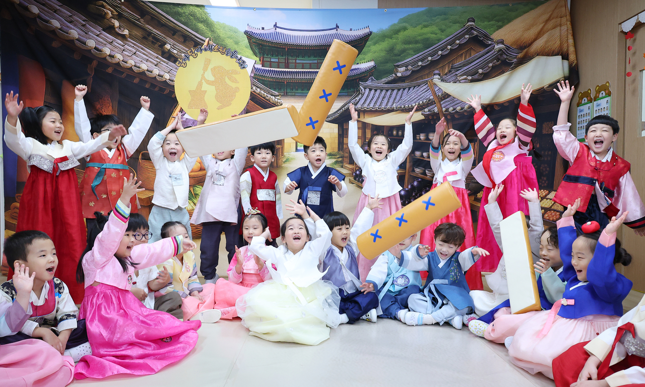 Children dressed in hanbok play yutnori, a traditional Korean game often played during the holiday, at a day care center in Busan on Wednesday. (Yonhap)