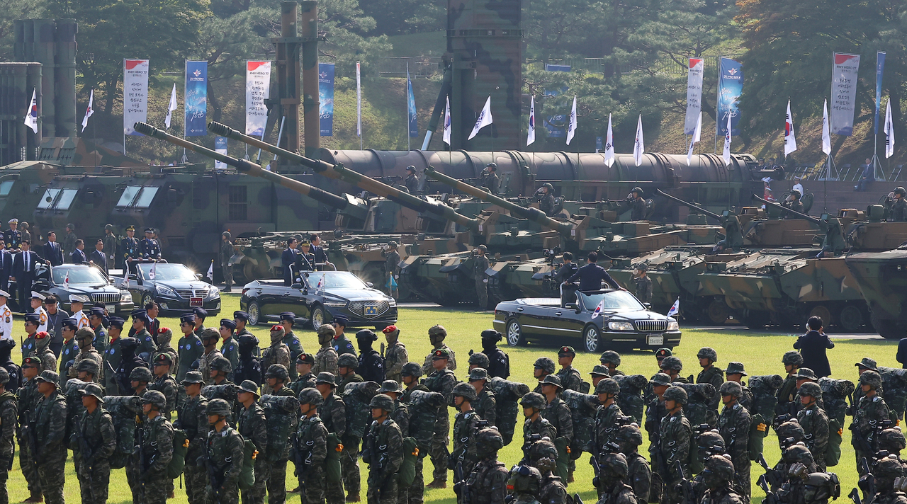 President Lee Jae Myung and Defense Minister Ahn Gyu-back, standing in a vehicle at the front of a procession, inspect soldiers and military equipment in formation during a military parade held at the Gyeryong military headquarters in South Chungcheong Province on Wednesday. (Yonhap)