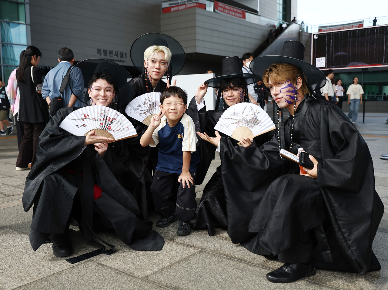 Male dancers, dressed as the Saja Boys from Netflix's hit animation film "Kpop Demon Hunters," pose for a photo with a visitor during a cosplay contest hosted by the National Museum of Korea on Saturday. (Yonhap)