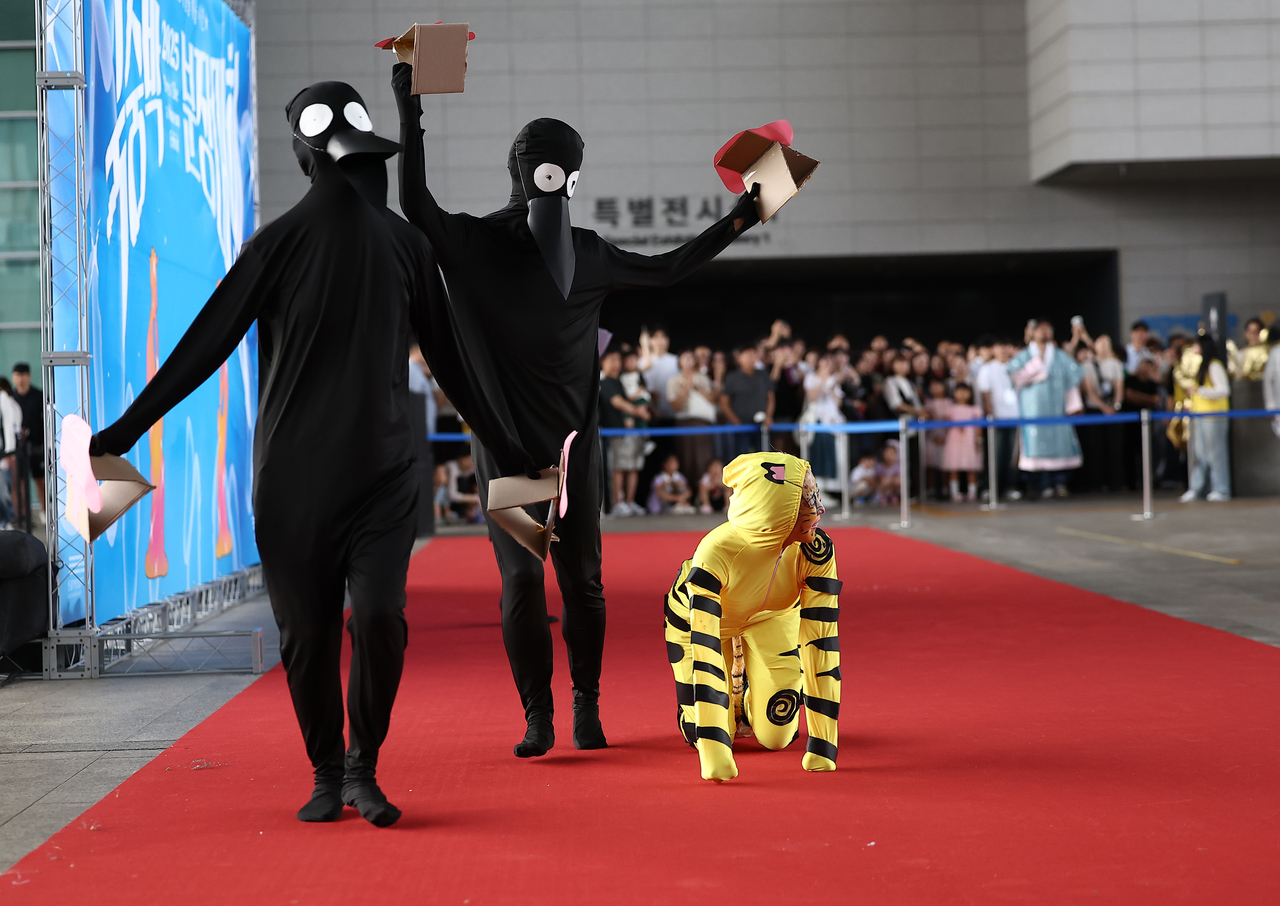A three-member team enters dressed as the tiger and magpies from the traditional folk painting “Hojakdo.”  (Yonhap)