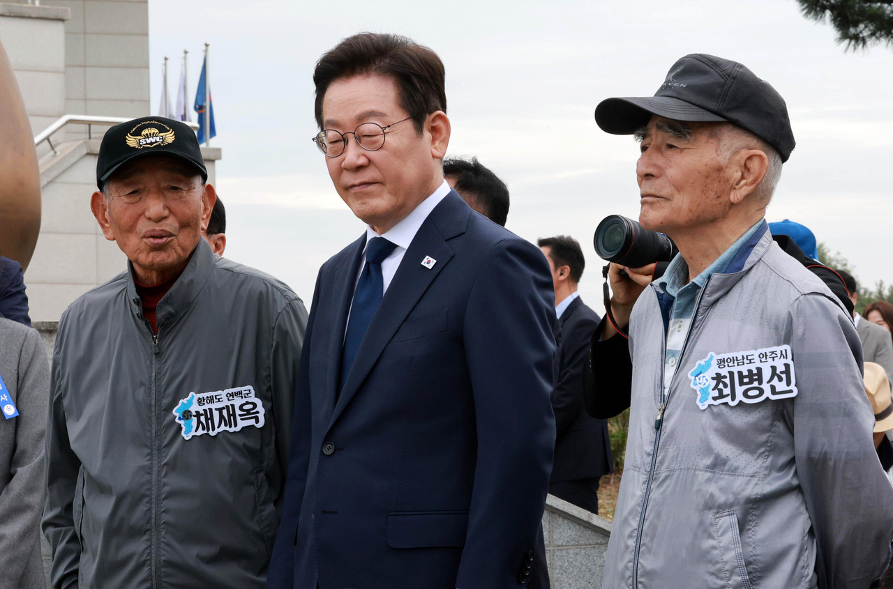 President Lee Jae Myung talks with displaced families at the Peace Observatory on Ganghwa Island while looking at North Korea on Oct. 3. (Yonhap)