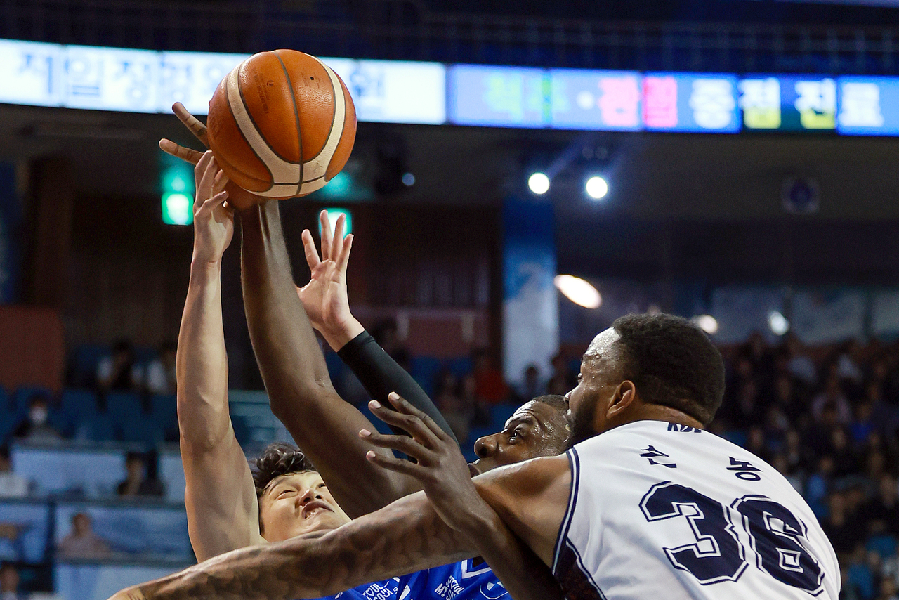 Busan KCC’s Shaun Long (right) battles Seoul Samsung’s Nicholson (center) and Choi Hyun-min for a rebound during the 2025-2026 KBL season opener at Jamsil Stadium in Seoul on Friday. (Yonhap)