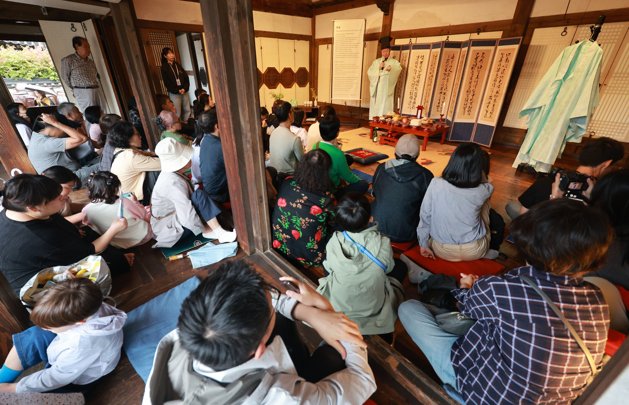 Visitors listen to stories about the traditional ancestral table, charyesang, at Namsangol Hanok Village in Seoul on Monday. (Yonhap)