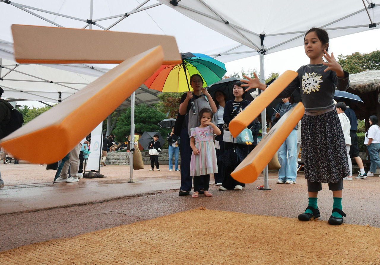 Visitors play yutnori, a traditional four-stick Korean board game, during a Chuseok cultural celebration with hanbok and folk performances.