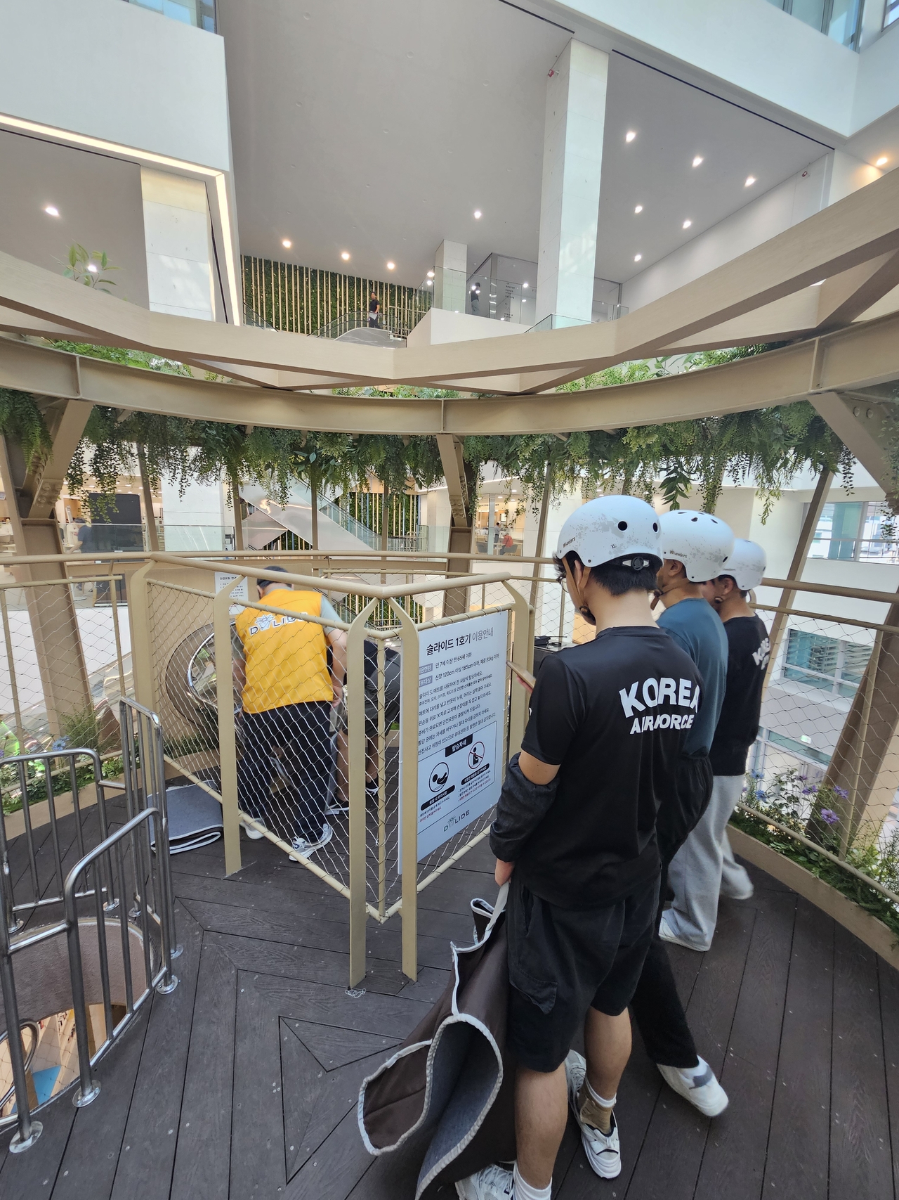 Visitors wait to ride D-Lide, wearing helmets and holding mats. (Choi Jae-hee / The Korea Herald)