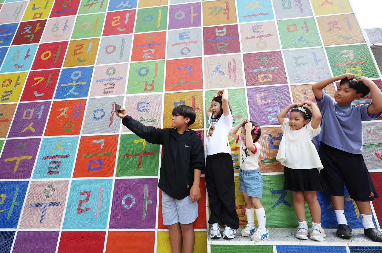 Children pose for photos in front of a Hangeul-themed mural at the Gyeonggi Children’s Museum in Yongin, Gyeonggi Province, on Wednesday, a day before Hangeul Day. (Yonhap)