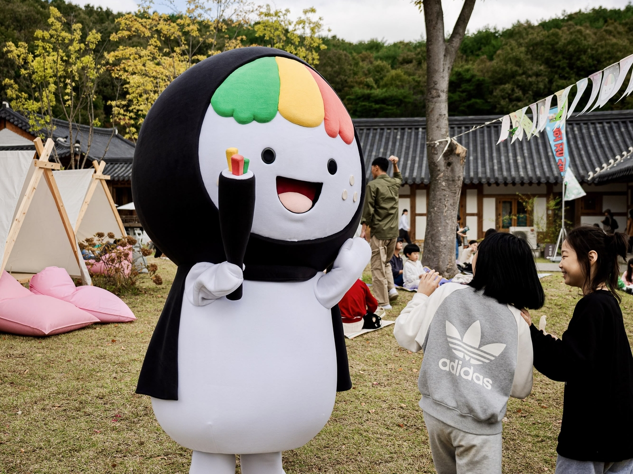 Kkodari, the gimbap mascot of Gimcheon, North Gyeongsang Province, greets visitors at the 2024 Gimcheon Gimbap Festival that has unexpectedly gone viral. Dressed as the “tail end” of a gimbap roll, the character embodies the festival’s cheeky rebrand of local identity through food and fun. (Gimcheon)