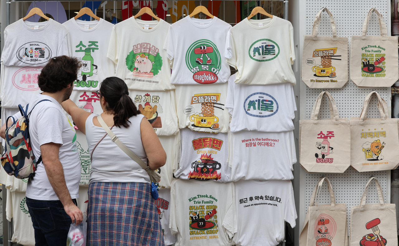 Tourists check T-shirts printed with Korean characters displayed in a store in Samcheong-dong in Seoul on Hangeul Day, Thursday. (Yonhap)