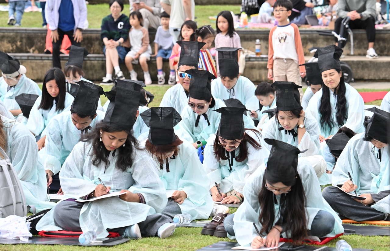 Attendees dressed in traditional scholar attire take part in a Hangeul quiz at the 2nd Sejong Hangeul Daejeon held at Sejong Lake Park’s Maehwa Stage on Thursday. (Im Se-jun/The Korea Herald)