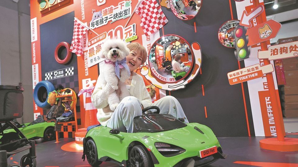A pet owner poses for photographs with her dog during a pet expo in Shanghai.   (China Daily)