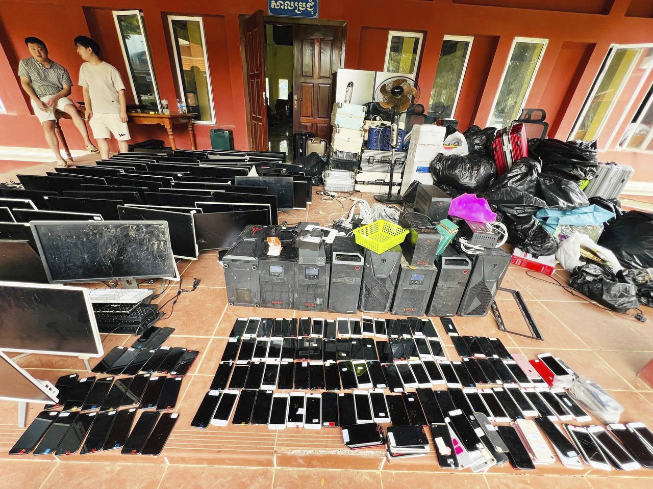 In this photo provided by state news service Agence Kampuchea Press, alleged online scammers stand next to their tools collected by authorities at its site in a classroom on the outskirts of Phnom Penh, Cambodia, on July 18. This photo is not related to the story. (AP-Yonhap)