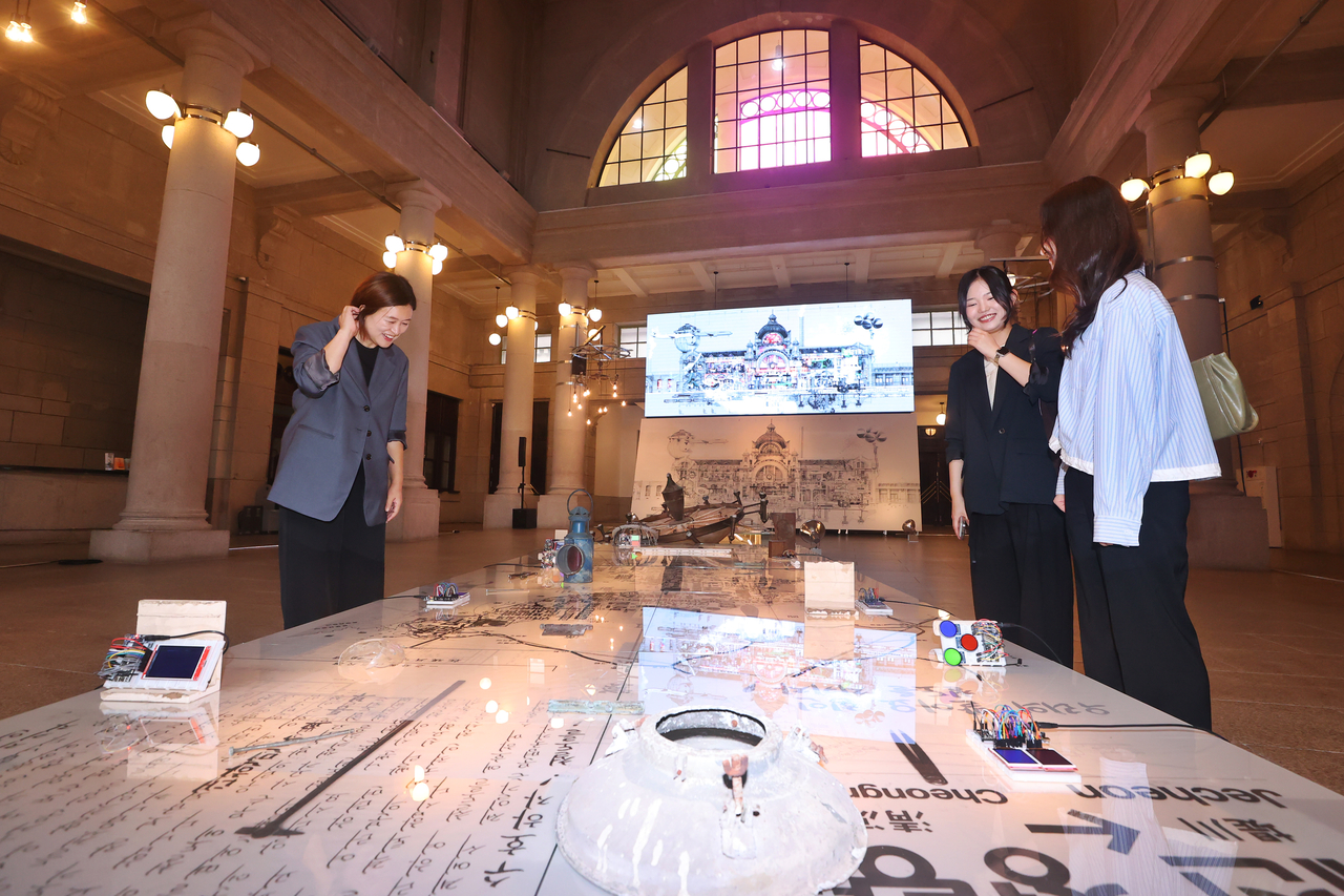 Visitors to the old Seoul Station's centinnial exhibition look at a floor installment on Tuesday. (Yonhap)