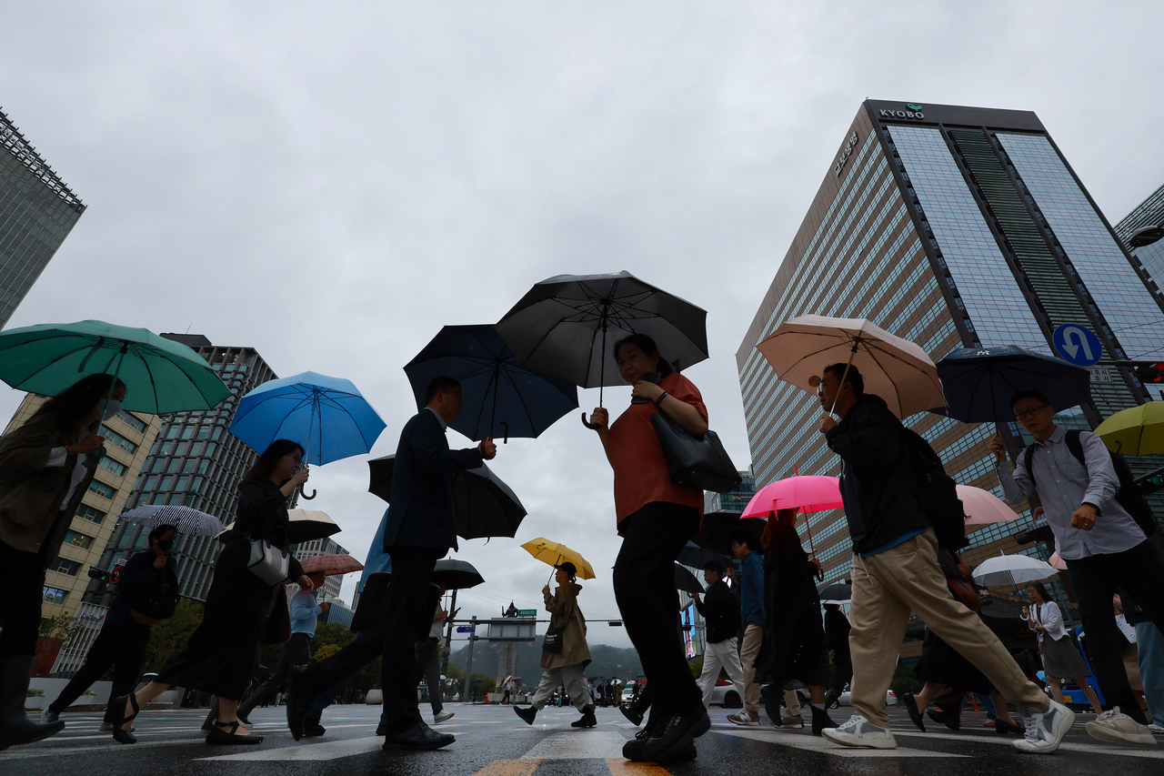 People holding umbrellas cross the street in central Seoul on Monday as they head to work after a long Chuseok holiday. (Yonhap)