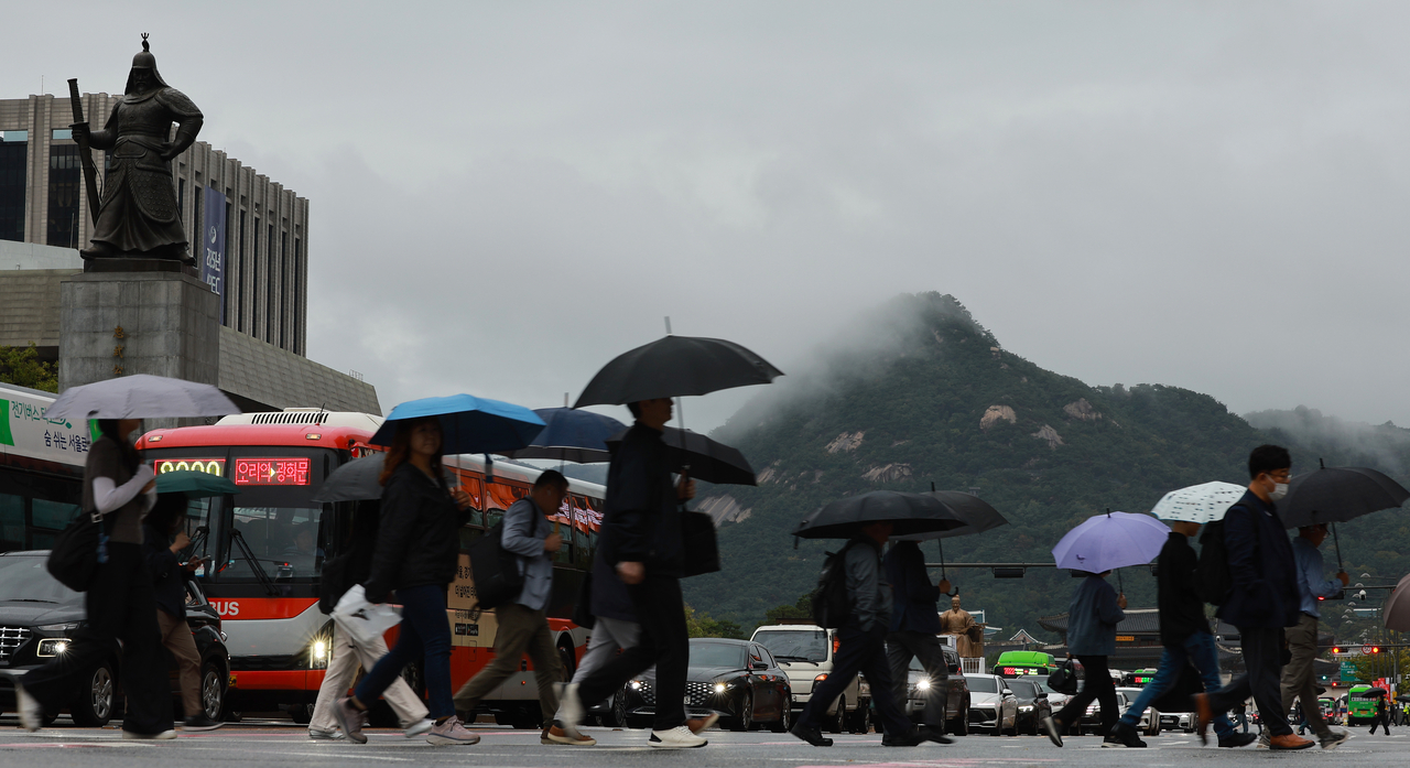 People with umbrellas traverse Gwanghwamun Square, central Seoul on Monday as they head to work after a long Chuseok holiday. (Yonhap)