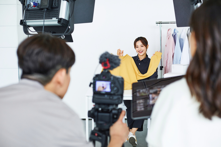 A woman hosts a livestream in front of a camera. (Getty Images Bank)