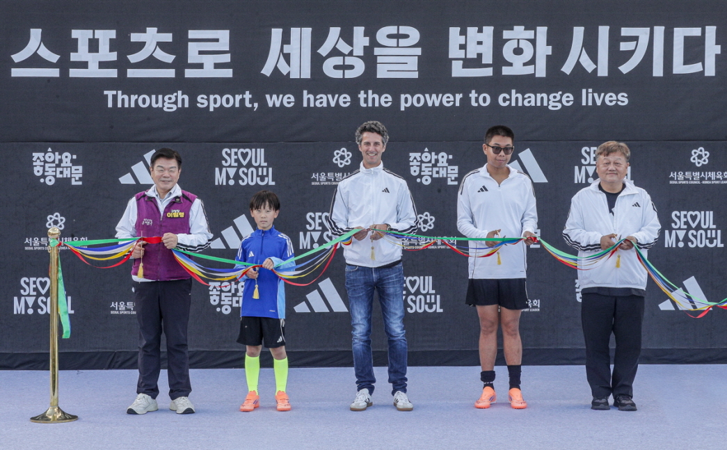 Adidas Korea Managing Director Markus Morent (center) cuts the ceremonial ribbons with attendees, including player representatives from local children’s and disabled soccer teams, at the reopening ceremony of a futsal field at Hwigyeong 2 Riverside Park in Seoul on Thursday. (Adidas Korea)
