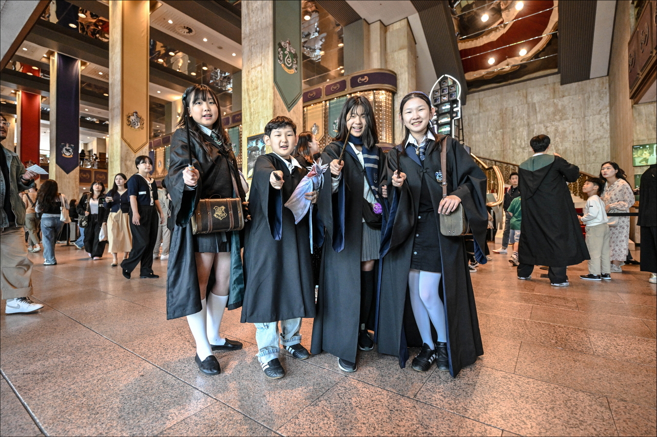 Audience members wearing wizarding robes strike poses with their wands, ahead of "Harry Potter and the Half-Blood Prince in Concert," in May at the Sejong Center in Seoul. (Sejong Center for Performing Arts)