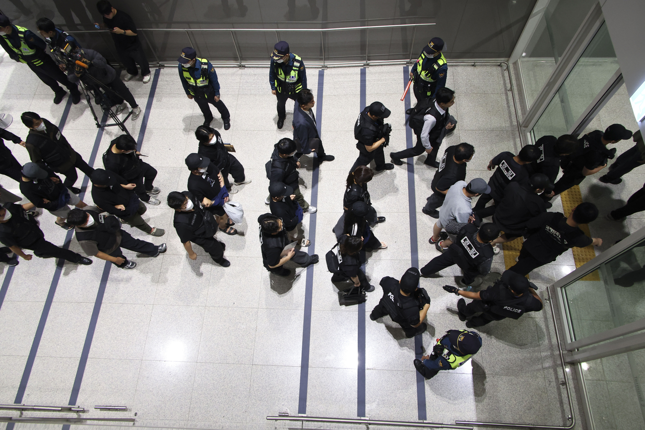 South Koreans involved in online scam operations in Cambodia are escorted by police officers upon arrival at Incheon International Airport's Terminal 2 on Saturday morning. (Yonhap)