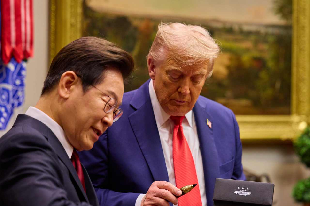 President Lee Jae Myung (left) gives a pen to US President Donald Trump as an impromptu gift during their summit at the White House in August. (Presidential office)