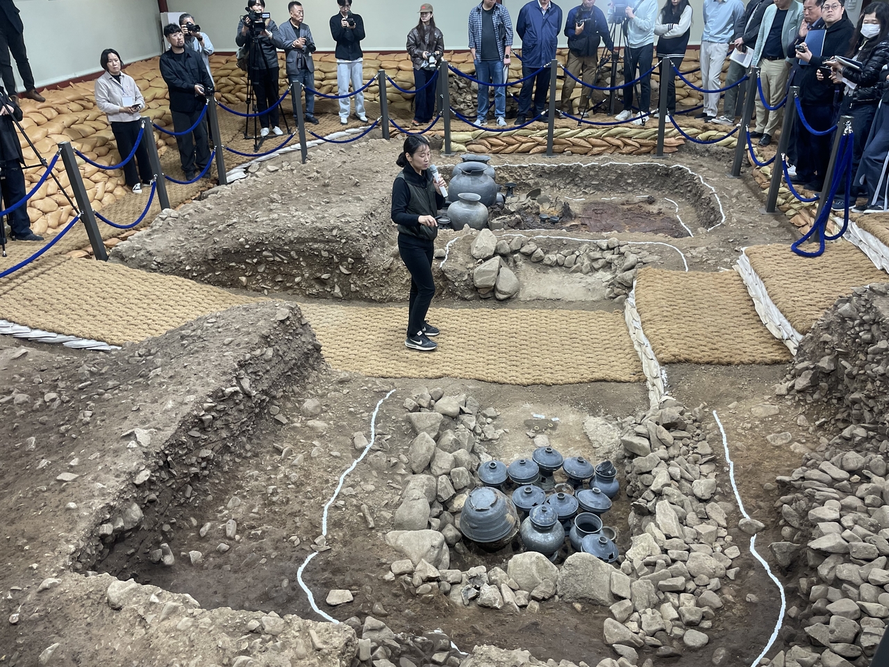 Lee Min-hyung (center), a researcher with the Silla Cultural Heritage Research Institute, describes artifacts found in the No. 1 outer coffin tomb at Hwangnam-dong No. 120 tomb site on Monday. (Hong Yoo/The Korea Herald)