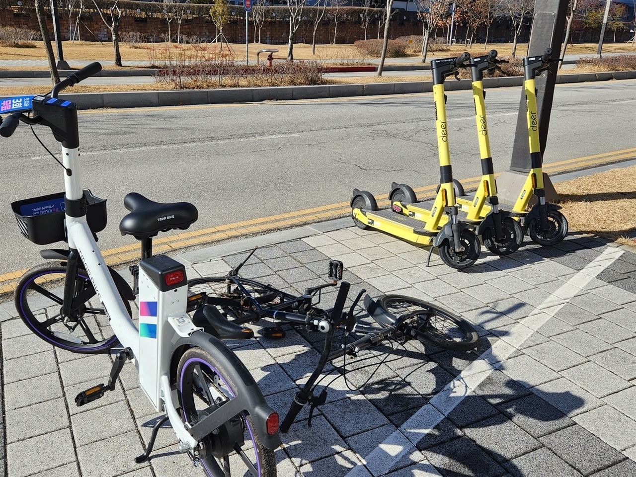 Shared e-scooters and e-bikes are seen parked haphazardly along a walkway in Seoul, with one bike toppled over and obstructing part of the way. (X)