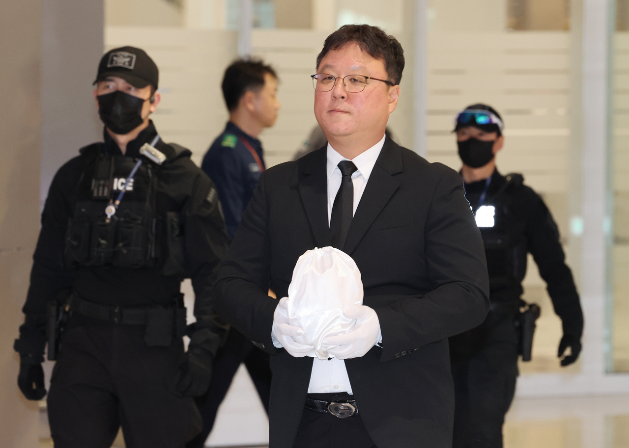An official carries the urn holding the ashes of a Korean university student who was tortured and killed in a Cambodian crime compound, at Incheon Airport on Tuesday. (Yonhap)