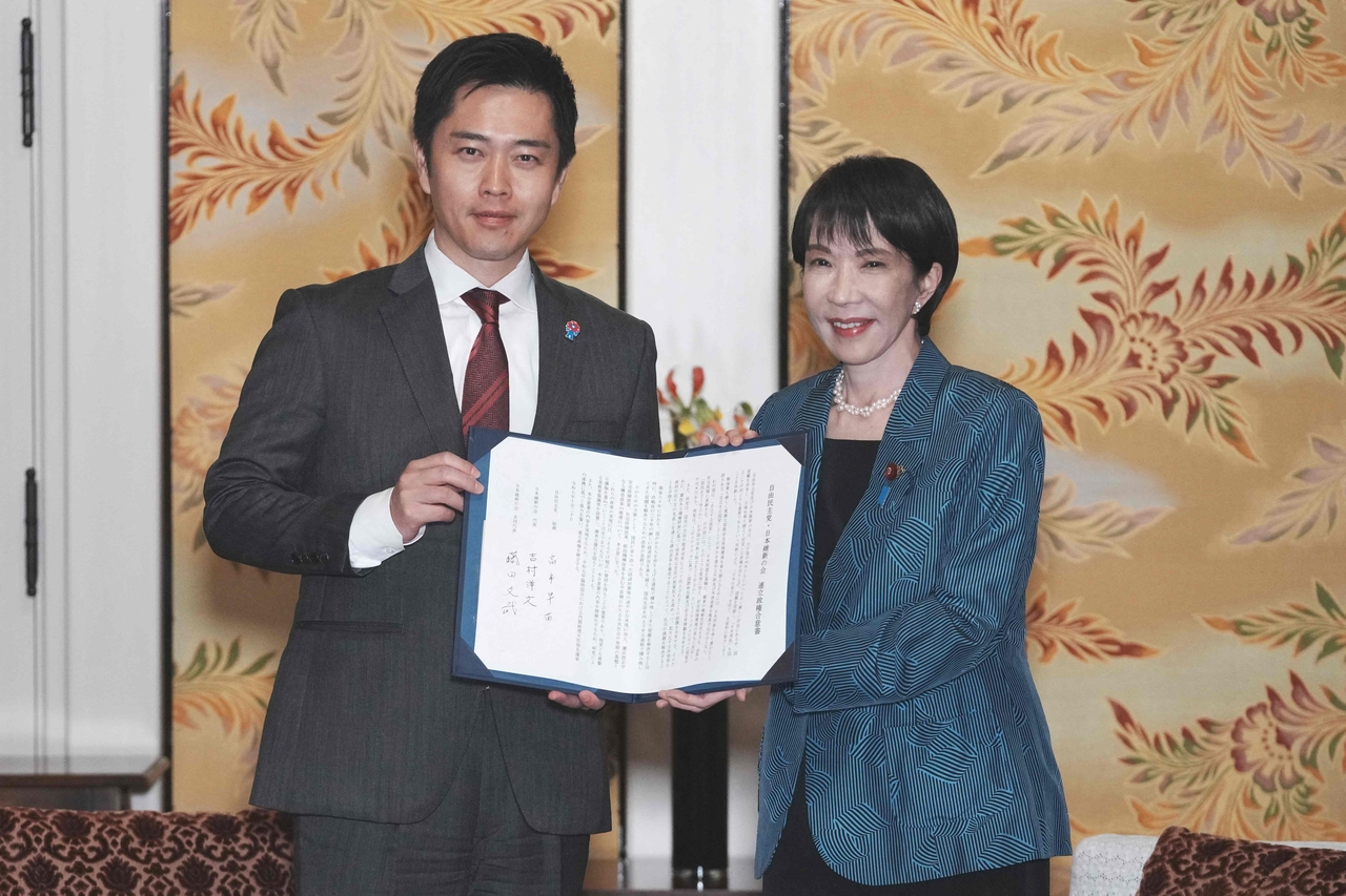 Japan's ruling Liberal Democratic Party President Sanae Takaichi (right) and Japan Innovation Party leader Hirofumi Yoshimura pose for the media after signing a policy agreement between the two parties at the Diet in Tokyo on Monday. (AFP)