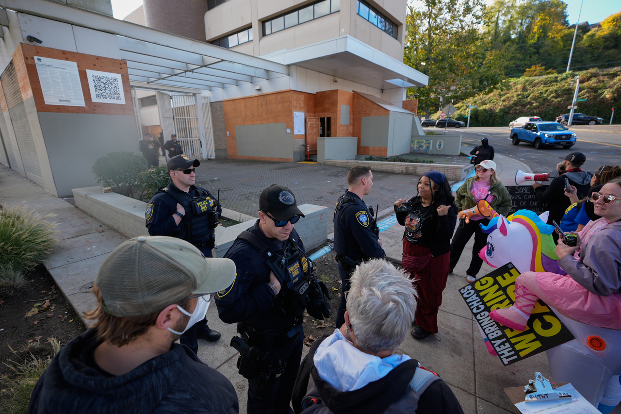 Law enforcement officers talk with protesters outside an Immigration and Customs Enforcement facility in Portland, Monday. (AP-Yonhap)