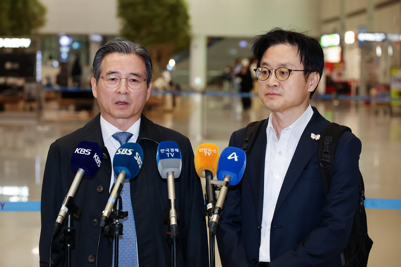 Kim Yong-beom (L), presidential chief of staff for policy, and Industry Minister Kim Jung-kwan speak to reporters at Incheon International Airport on Friday. (Yonhap)