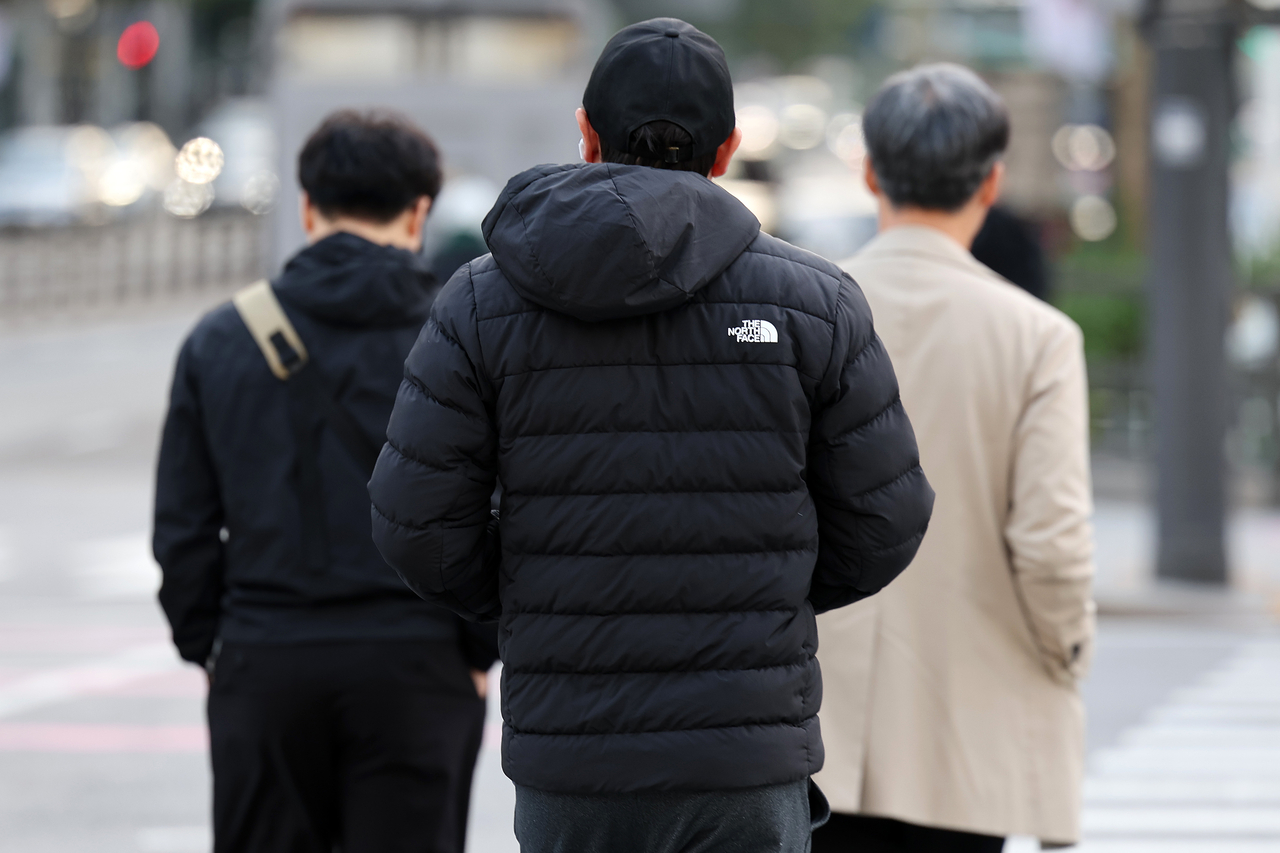 A pedestrian is seen wearing a thick, padded winter jacket near Gwanghwamun Square in Jongno-gu, central Seoul on Oct. 20. (Yonhap)