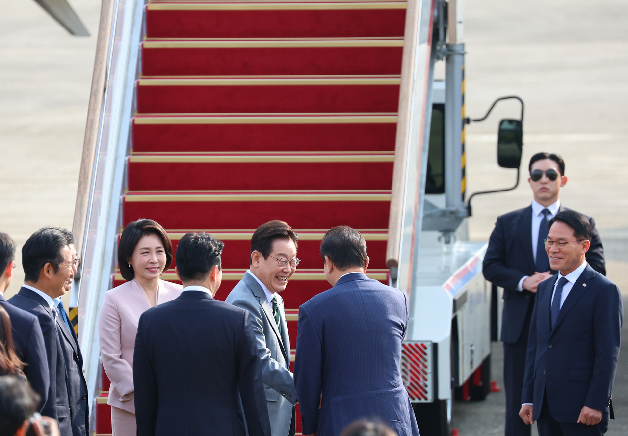 President Lee Jae Myung (center, left) and first lady Kim Hea Kyung greet officials before boarding the presidential plane at Seoul Air Base in Seongnam, Gyeonggi Province, Sunday, ahead of their trip to Malaysia to attend the ASEAN summit. (Yonhap)