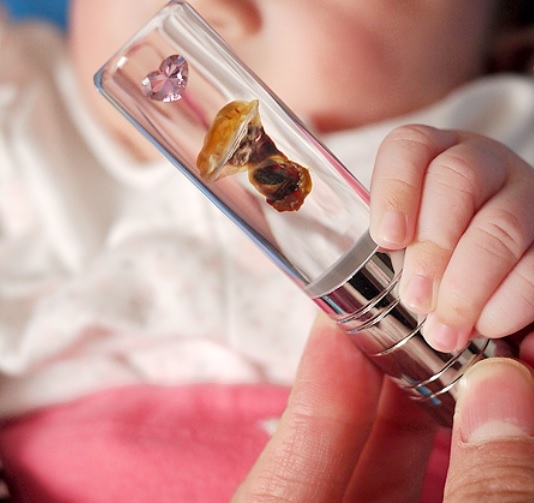 A baby holds a personalized stamp made with a part of their own umbilical cord. (Naver)