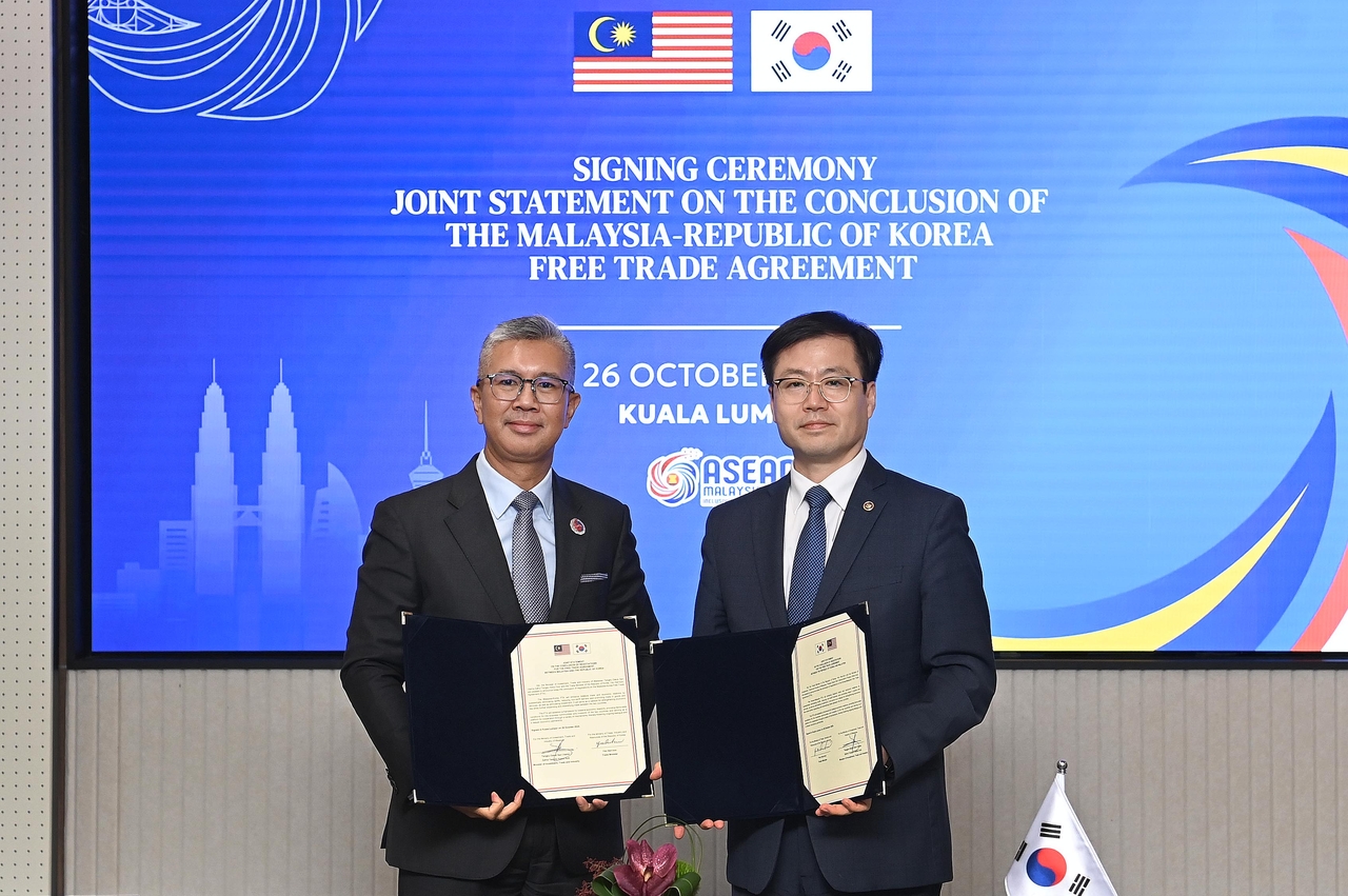 Trade Minister Yeo Han-koo (right) poses with Tengku Zafrul Aziz, Malaysia's minister of investment, trade and industry, after signing a joint declaration on the bilateral free trade agreement, in Kuala Lumpur, Malaysia, on Monday, in this photo provided by Seoul's industry ministry.  (Ministry of Trade, Energy and Industry)