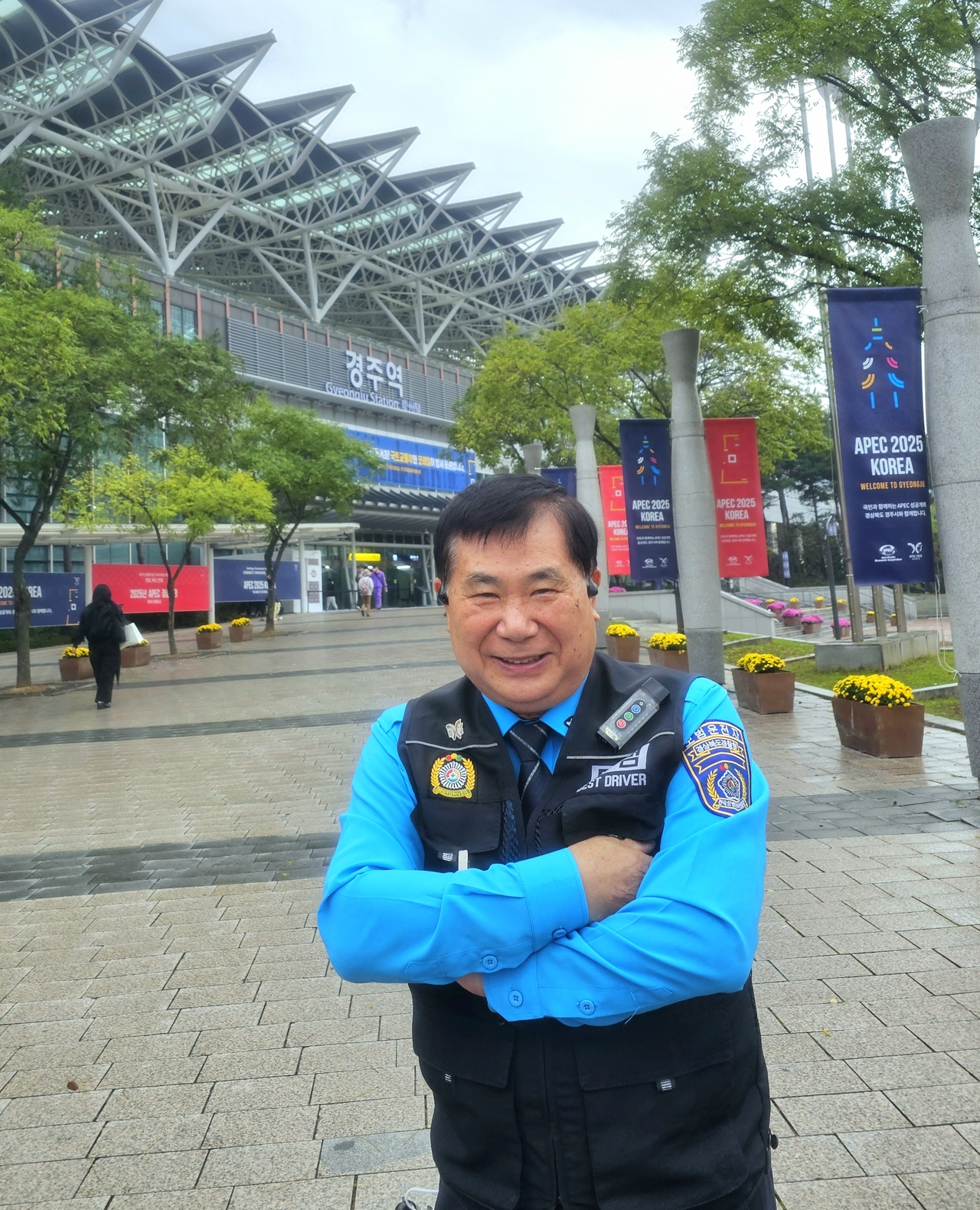 Park Sang-jin stands for a photo in front of Gyeongju Station, with APEC banners lining the street behind him. (Choi Jae-hee/The Korea Herald)