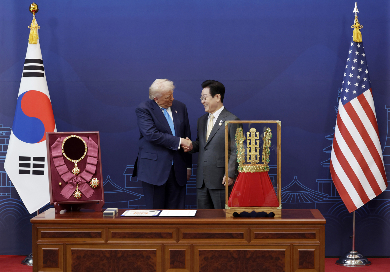 South Korean President Lee Jae Myung (right) shakes hands with US President Donald Trump after conferring the Grand Mugunghwa Medal, South Korea's highest order of civil merit, on Trump ahead of their talks at the National Museum in Gyeongju, North Gyeongsang Province, on Wednesday. In front of Lee is a replica of a gold crown from a royal tomb from the Silla Kingdom (57 BC-AD 935) that was gifted to the US leader. (Pool photo via Yonhap)