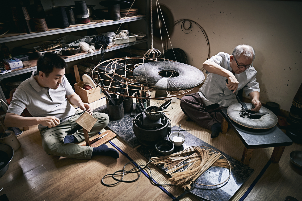 Park Chang-young (right), holder of the National Intangible Cultural Heritage title in gannil (hat-making), and his son and apprentice Park Hyung-park, make gat. (Korea Craft and Design Foundation)