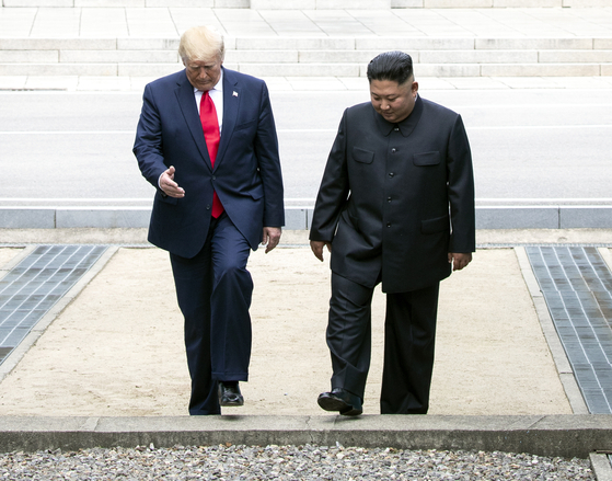 US President Donald Trump (left) crosses back into South Korean territory at Panmunjom in the Demilitarized Zone separating the two Koreas, alongside North Korean leader Kim Jong-un in June 2019. (Yonhap)