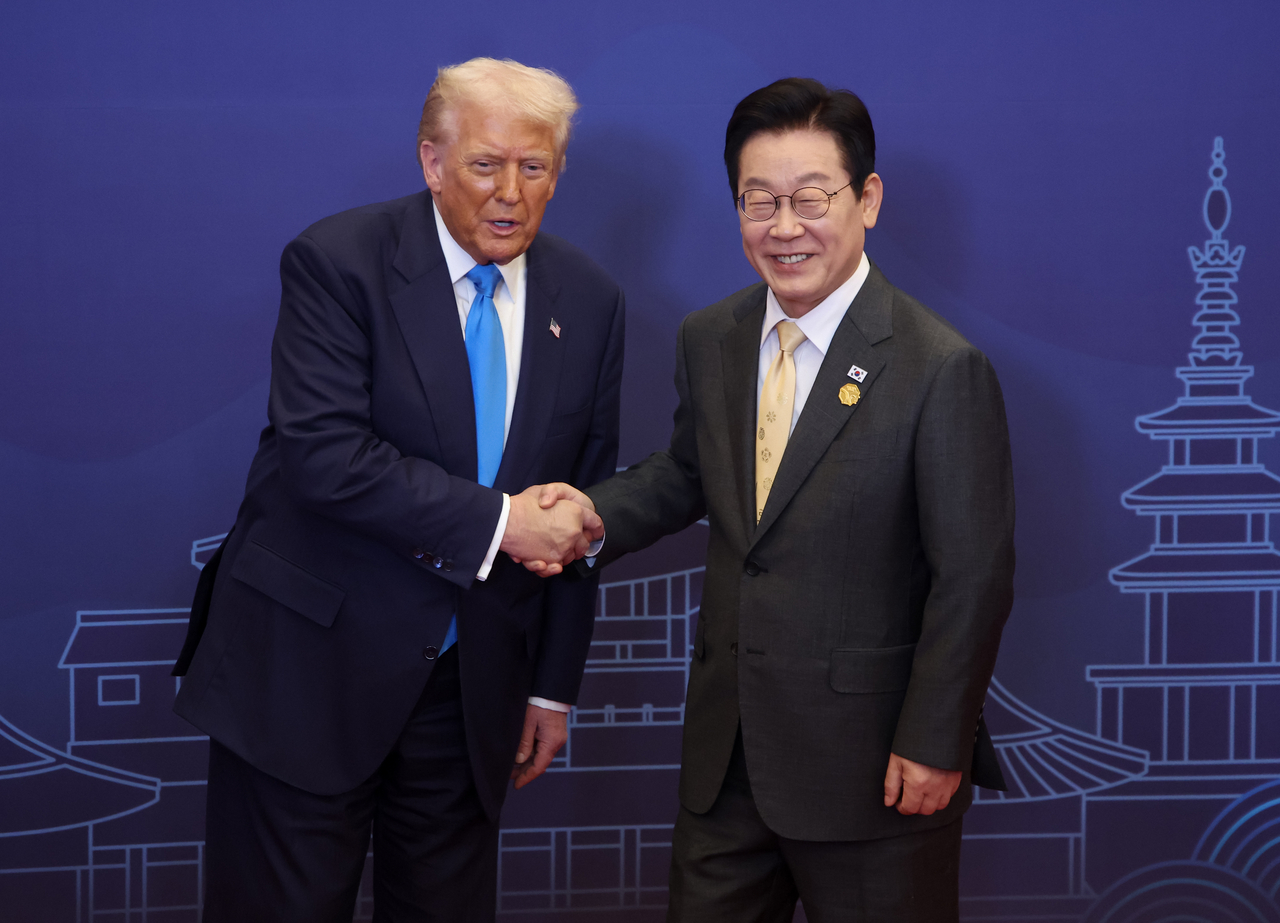 This photo, taken on Wednesday, shows South Korean President Lee Jae Myung (R) shaking hands with US President Donald Trump in the southeastern city of Gyeongju. (Yonhap)