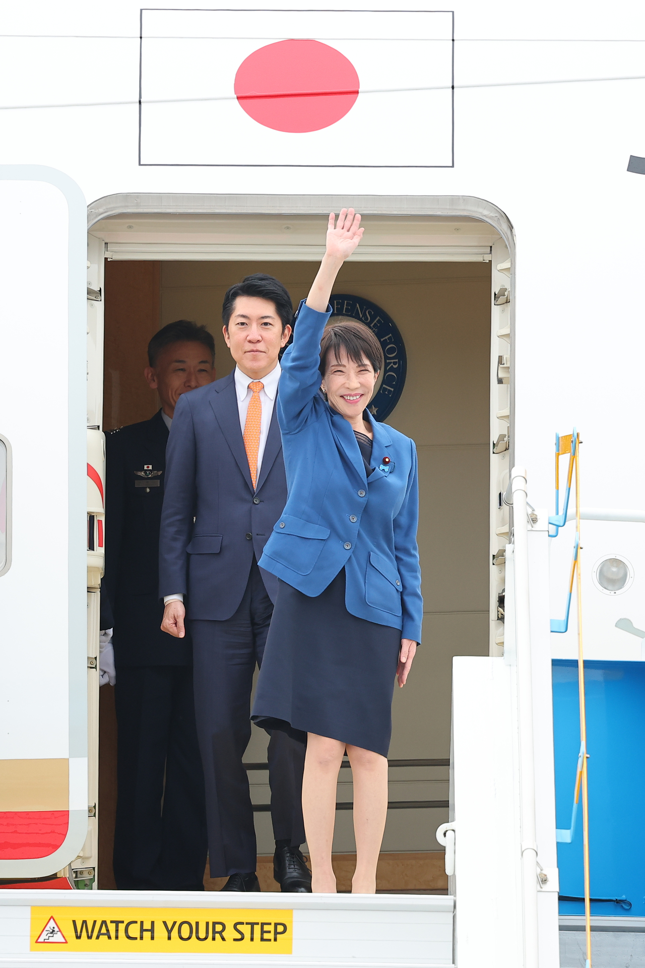 Japanese Prime Minister Sanae Takaichi waves from the Japanese Air Force One after arriving at Gimhae International Airport in Busan on Thursday. (Yonhap)