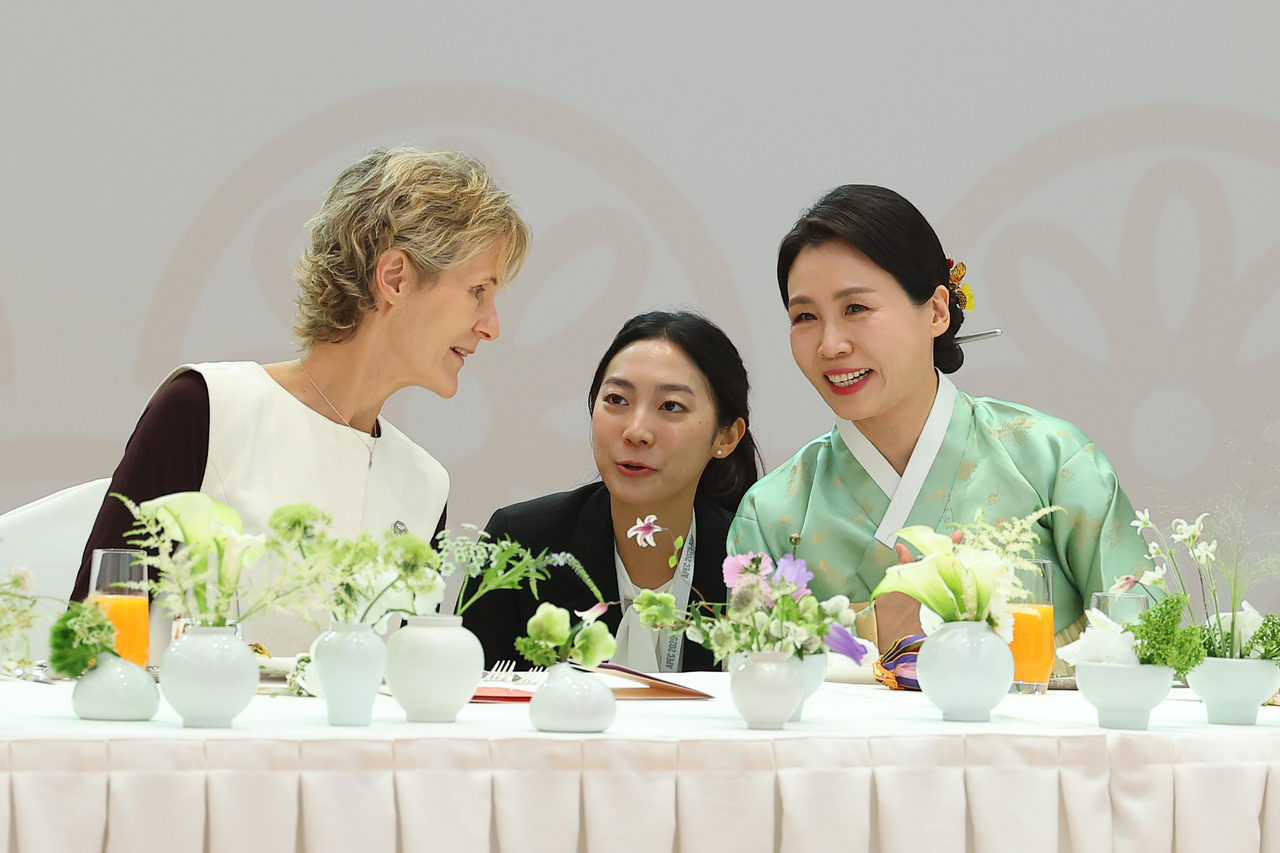 First lady Kim Hea Kyung (right) engages in conversation with Diana Fox Carney, the wife of Canadian Prime Minister Mark Carney, during a luncheon with companions of leaders attending the APEC summit on Friday. (Yonhap)