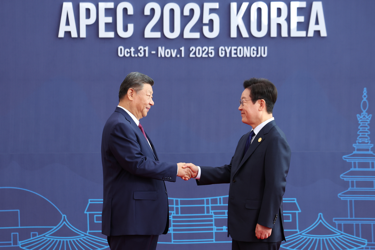 President Lee Jae Myung (right) greets Chinese President Xi Jinping at the 2025 Asia-Pacific Economic Cooperation summit in Gyeongju, North Gyeongsang Province, Friday. (Yonhap)