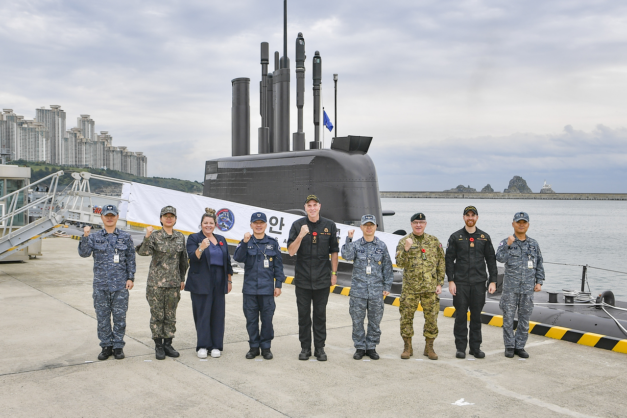 Vice Adm. Angus Topshee (center), commander of the Royal Canadian Navy, poses for a picture with Korean and Canadian military officials in front of Ahn Mu, South Korea's 3,000-ton submarine, at a military base in Busan on Friday. (Yonhap)