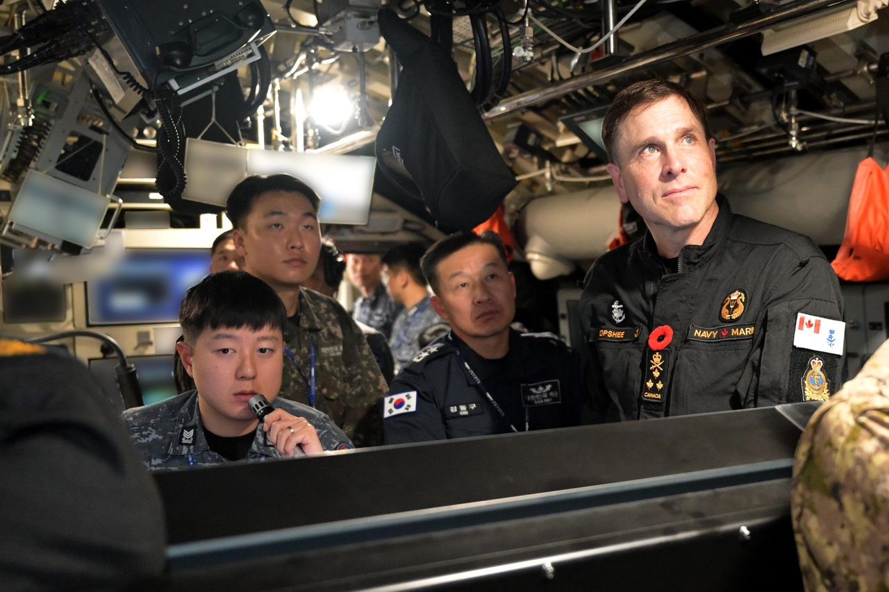 Vice Adm. Angus Topshee (right), commander of the Royal Canadian Navy, tours the interior of the Ahn Mu, a 3,000-ton Dosan Ahn Chang-ho class submarine, on Friday at a military base in Busan. (Yonhap)