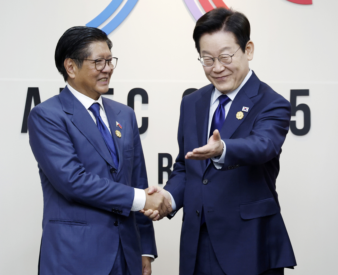 South Korean President Lee Jae Myung (right) guides Philippine President Ferdinand Marcos Jr. to his seat before their bilateral summit in Gyeongju, North Gyeongsang Province, Friday. (Yonhap)