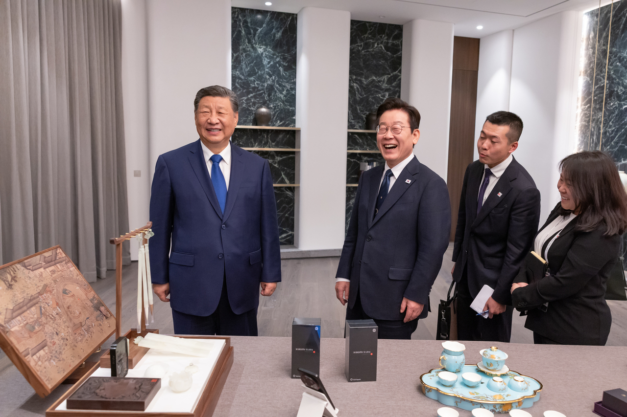 President Lee Jae Myung (right) and Chinese President Xi Jinping (left) smile as they exchange gifts after their summit meeting on the sidelines of the Asia-Pacific Economic Cooperation gathering on Saturday. (Yonhap)