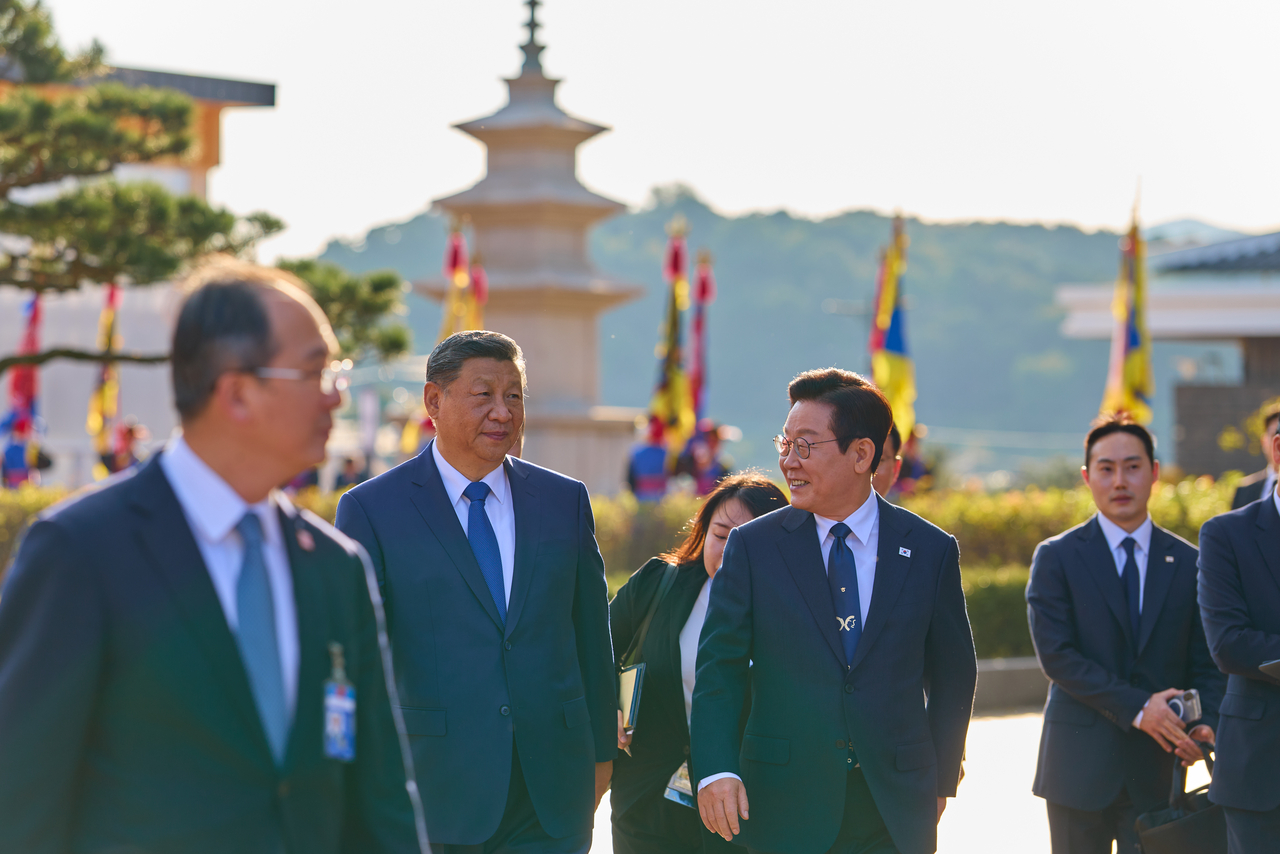 President Lee Jae Myung (2nd from right) speaks with Chinese President Xi Jinping (2nd from let) as they walk to the venue of their bilateral summit on the margins of the Asia-Pacific Economic Cooperation summit in the southeastern city of Gyeongju on Saturday. (Yonhap)