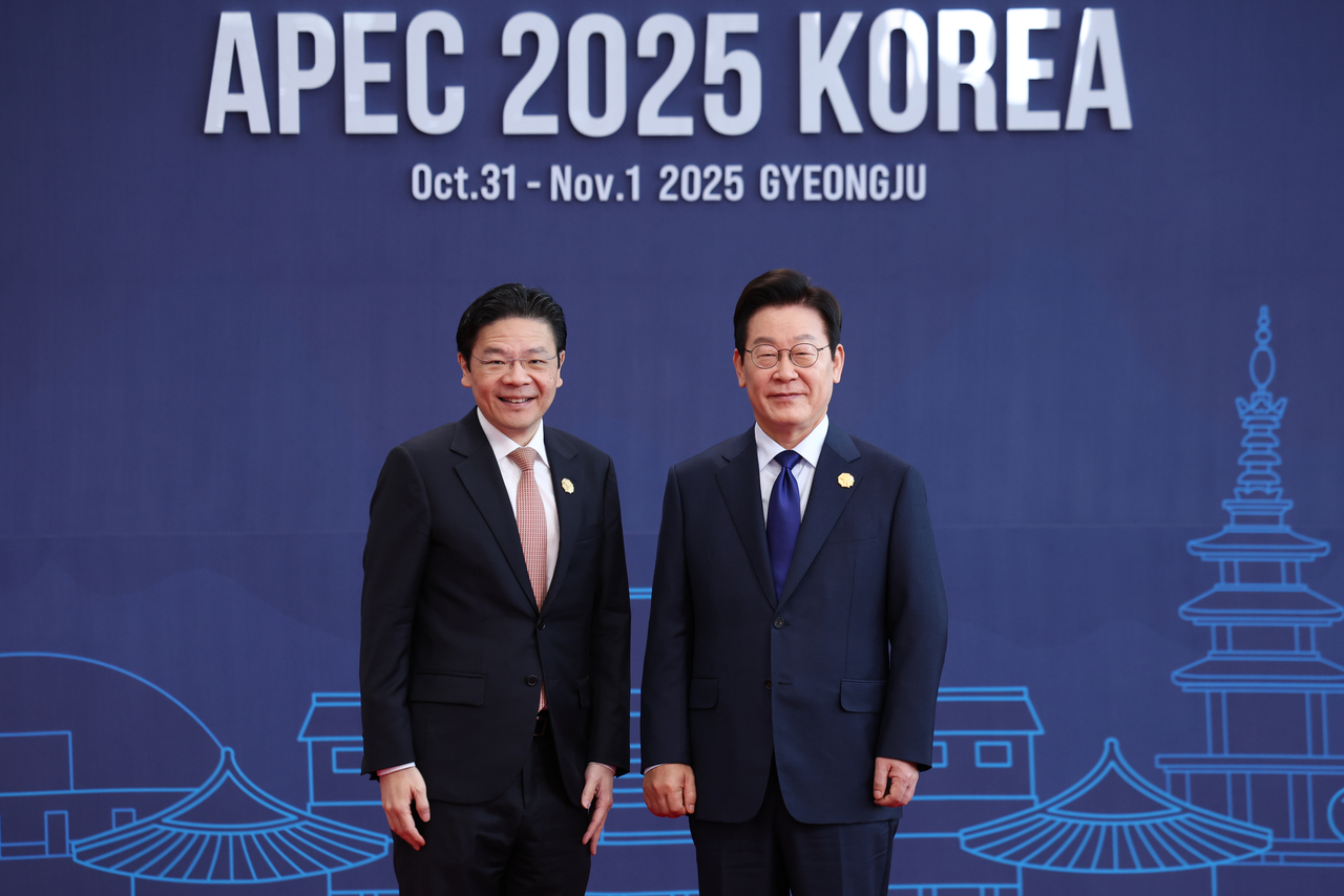 President Lee Jae Myung (right) poses for a photo with Singaporean Prime Minister Lawrence Wong at the Asia-Pacific Economic Cooperation gathering in the southeastern South Korean city of Gyeongju on Friday. (Yonhap)