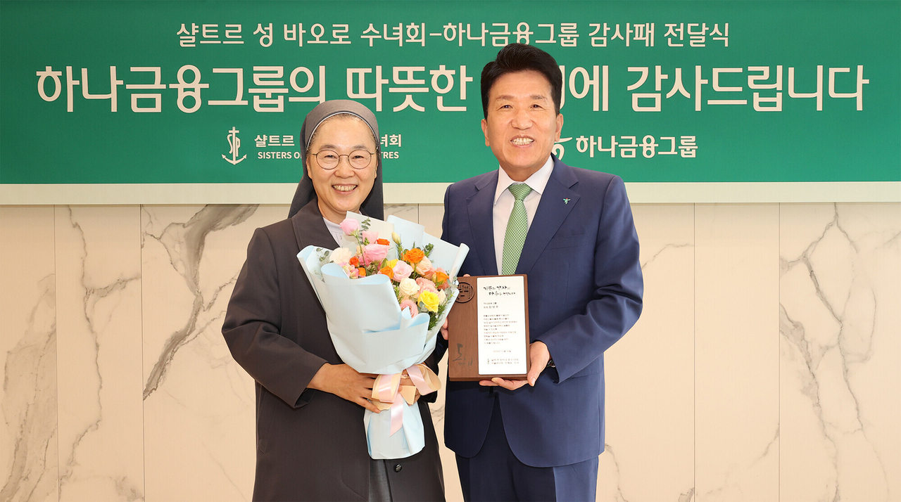 Hana Financial Group Chair Ham Young-joo (right) receives a plaque of appreciation from Min Hye-sook, provincial superior of the Sisters of Saint Paul of Chartres, at the group's Myeong-dong headquarters in Seoul on Friday. (Hana Financial Group)